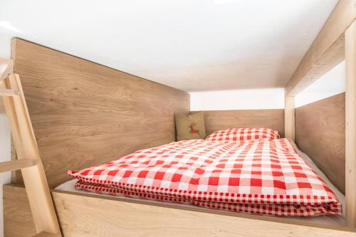 a bed with a red and white checkered blanket at Mittergasteggut in Pfarrwerfen