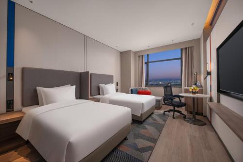 a hotel room with two beds and a flat screen tv at Holiday Inn Express Qingdao City Balcony by IHG in Qingdao