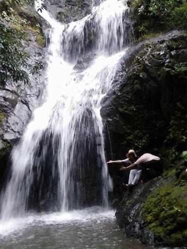 a person standing in front of a waterfall at El Refugio La Brisa del Diablo in Valle Hornito