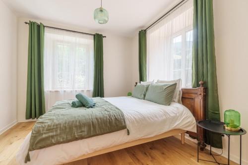 een slaapkamer met een bed met groene gordijnen bij Gîte de l'Oriel - Gîte avec Grand Jardin in Sainte-Marie-aux-Mines