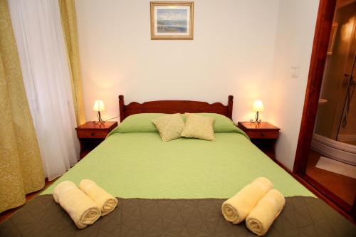 a bedroom with a green bed with towels on it at Rooms & Studio Stipcic in Trogir