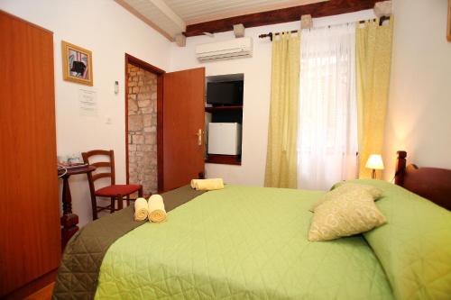 a bedroom with a green bed and a table and chairs at Rooms & Studio Stipcic in Trogir