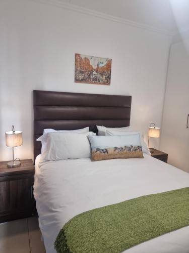 a bedroom with a large white bed with a green blanket at paradise in Ballito in Ballito