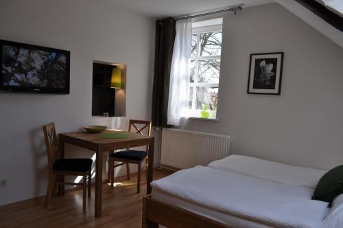 ein Schlafzimmer mit einem Tisch, einem Bett und einem Fenster in der Unterkunft Apartment Brauner Hirsch in Celle