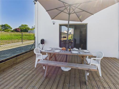une table en bois avec des chaises et un parasol sur une terrasse dans l'établissement 400m du Port du Guilvinec - Maison pour 6, au Guilvinec
