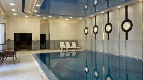 a swimming pool in a lobby with chairs and a table at Chinor Hotel Fergana in Fergana