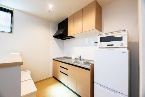 a small kitchen with a refrigerator and a microwave at Irodori Hotel TEN in Fukuoka