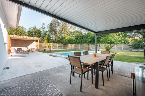 a patio with a table and chairs and a pool at Maison entre Vignobles et Dune in Belin-Beliet