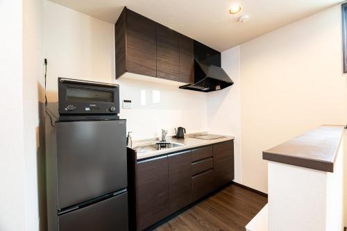 a small kitchen with a sink and a refrigerator at Irodori Hotel AKEBONO in Fukuoka