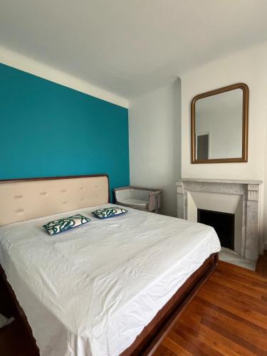 - une chambre dotée d'un lit avec un mur bleu et un miroir dans l'établissement Villa belle époque idéalement située plage et centre ville, à Saint-Raphaël
