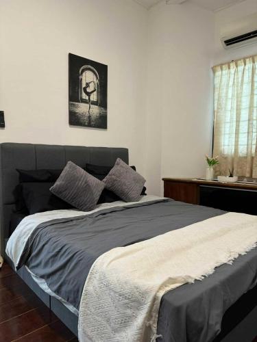 a bedroom with a bed with a gray blanket and a window at Kemaman AY Home in Cukai