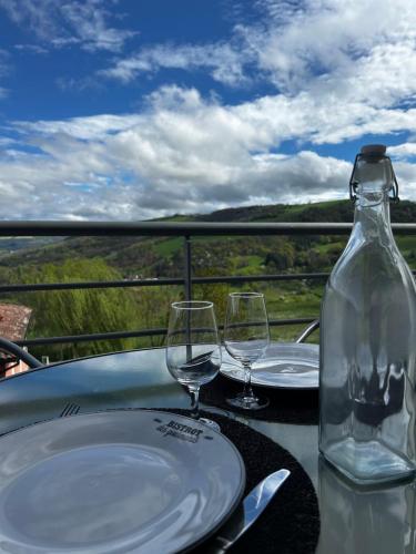 a table with two wine glasses and a bottle at L'Erable T2 climatisé in Trébas
