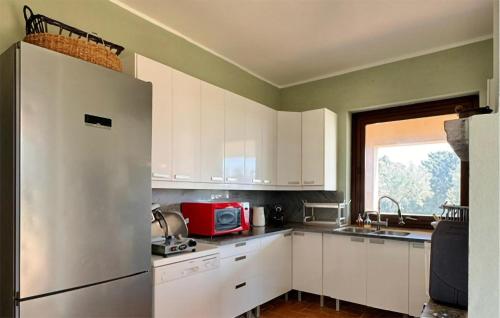 a kitchen with white cabinets and a stainless steel refrigerator at Beautiful Home In Montalto Di Castro in Montalto di Castro