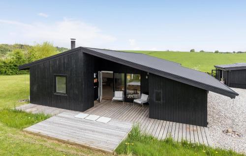a black house with a wooden deck in a field at 4 Bedroom Lovely Home In Rønde in Rønde
