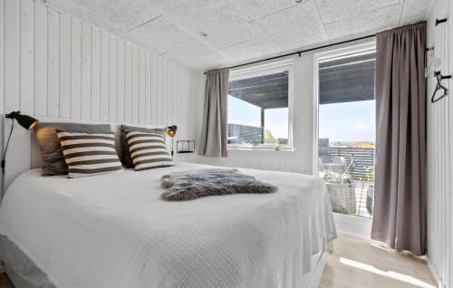a bedroom with a white bed with a large window at Amazing Home In Karrebæksminde in Karrebæksminde