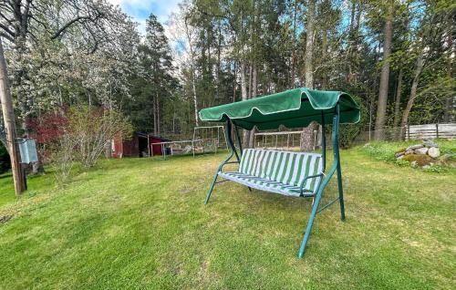 a park bench with a green canopy in the grass at Pet Friendly Home In Söderköping in Söderköping