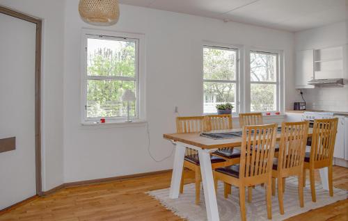 a white kitchen with a wooden table and chairs at 2 Bedroom Awesome Apartment In Ystad in Ystad