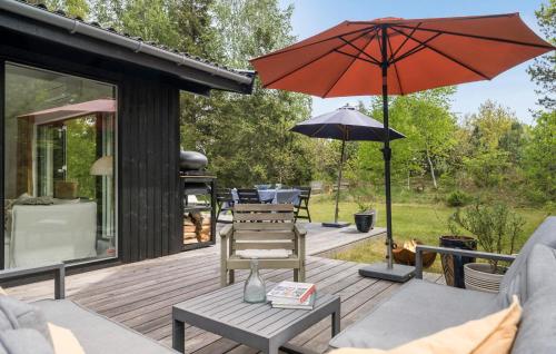 a patio with an umbrella and chairs on a deck at 3 Bedroom Gorgeous Home In Højby in Højby