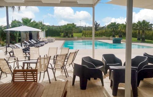 a patio with tables and chairs and a swimming pool at Gorgeous Home In Acate in Acate