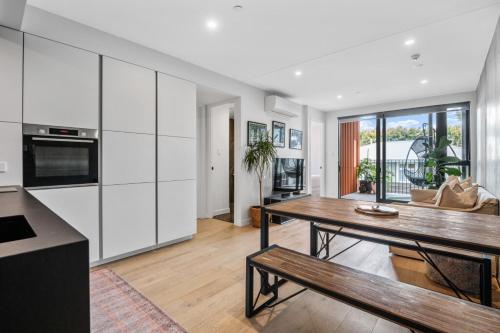 a kitchen with white cabinets and a wooden table at Tranquil 2 Bd Apt with AC, WIFI, & 10min from CBD in Auckland