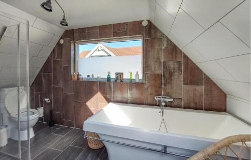 a bathroom with a tub and a toilet and a window at Amazing Home In Höganäs in Höganäs