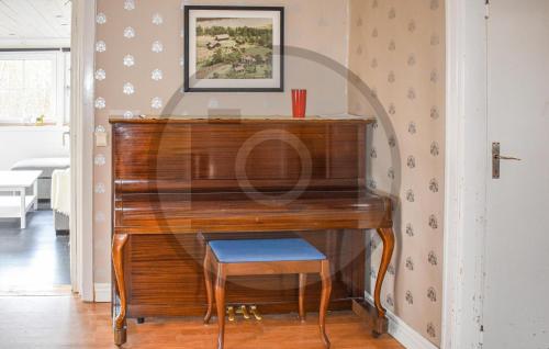 a wooden piano with a stool in front of it at 4 Bedroom Stunning Home In Åtvidaberg in Åtvidaberg