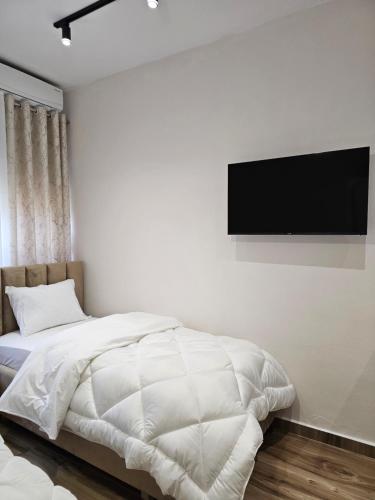 a bedroom with a bed and a flat screen tv on the wall at Star Room's in Durrës