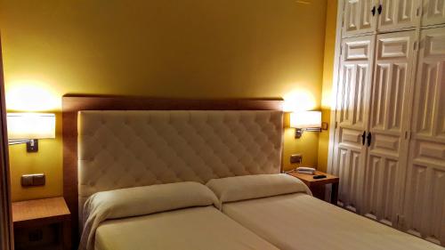 a bedroom with a white bed with two lights on it at Hospedería Santa Elena in San Carlos del Valle