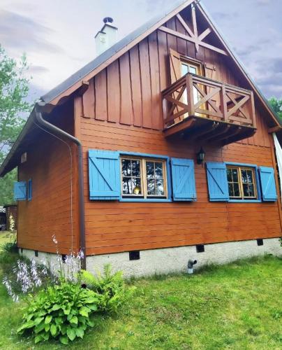 a wooden house with blue windows and a balcony at Fajno Chałupa in Konarzyny