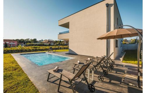 un groupe de chaises et un parasol à côté d'une piscine dans l'établissement Cozy Home In Kastelir With Sauna, à Kaštelir
