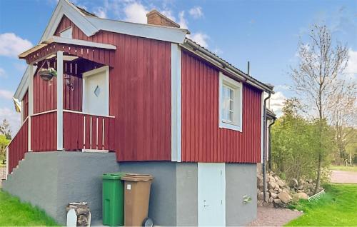 a red house with two trash cans in front of it at 1 Bedroom Amazing Home In Tålebo in Tålebo