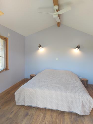 une chambre avec un lit blanc avec un ventilateur de plafond dans l'établissement Cabane Wood & Spa, à Chasselay