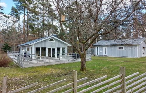 a white house with a fence in a yard at Amazing Home In Holmseryd With Wifi in Jälluntofta