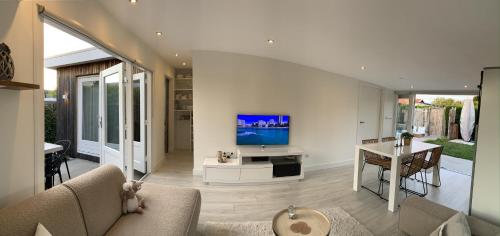 a living room with a couch and a tv on a wall at Beach House nr 69 in Ouddorp