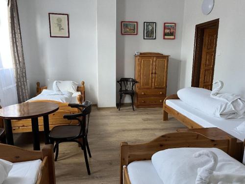 a room with three beds and a table and a table and chairs at Bömbi Vendégház a vár mellett in Sárospatak