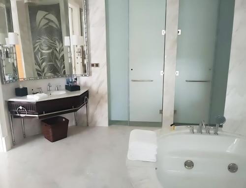 a bathroom with a sink and a tub and a mirror at Hotel Anda China Malabo in Malabo
