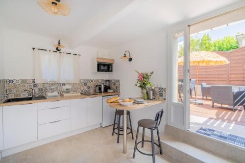 une cuisine avec des armoires blanches et une table avec des chaises dans l'établissement Monte Cristo - appt climatisé proche des plages, à Marseille