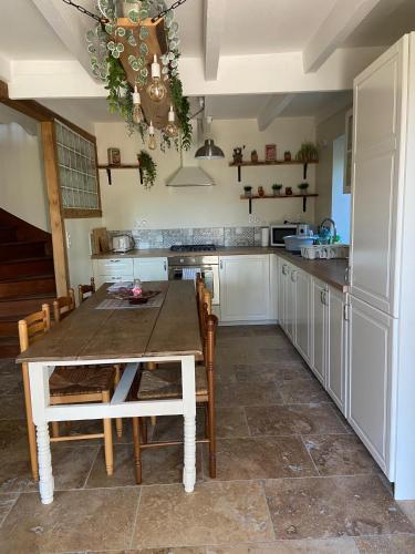 une cuisine avec une table et des chaises dans une pièce dans l'établissement Pinabre Farmhouse, à Plouguenast Langast