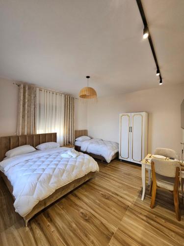 a bedroom with two beds and a table and a refrigerator at Star Room's in Durrës