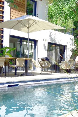 un patio avec une table, des chaises et un parasol dans l'établissement Beautiful house pool Aix-en-Provence, à Aix-en-Provence