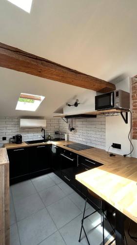 une cuisine avec des armoires noires et un comptoir en bois dans l'établissement T2 de charme, au cœur de ville avec climatisation, à Toulouse