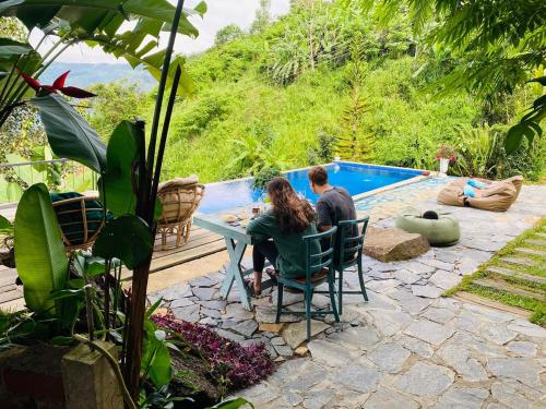 a man and woman sitting at a table by a pool at Awesome Place in Ella