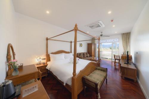 a bedroom with a canopy bed and a living room at Lanna Inthan Resort in Doi Saket