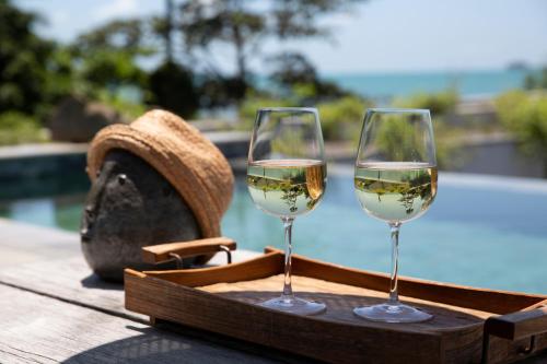 two glasses of wine on a tray next to a pool at Clay Beach Samui - Beachfront Villas in Amphoe Koh Samui