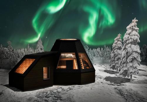 a cabin in the snow under the northern lights at Aurora Village Ivalo in Ivalo