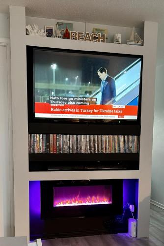 a television with a fireplace in a living room at Norfolk Nest 2 bedroom chalet new media wall in Hemsby