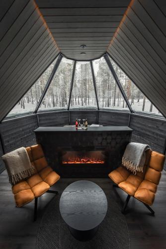 a room with a fireplace and two chairs and a table at Aurora Village Ivalo in Ivalo