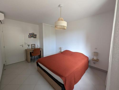 - une chambre avec un lit rouge et une table dans l'établissement Appartement neuf près du port de Porto Vecchio, à Porto-Vecchio