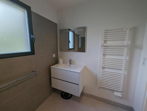 une salle de bain blanche avec un lavabo et un miroir dans l'établissement Appartement neuf près du port de Porto Vecchio, à Porto-Vecchio
