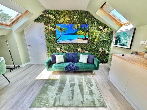 a living room with a green couch in front of a wall at Luxe Chic Retreat - Tropical Vibes & Skylight Serenity - WiFi - Large Smart TV - Minutes Walk to Town and Beach - Sleeps 3 in Bournemouth